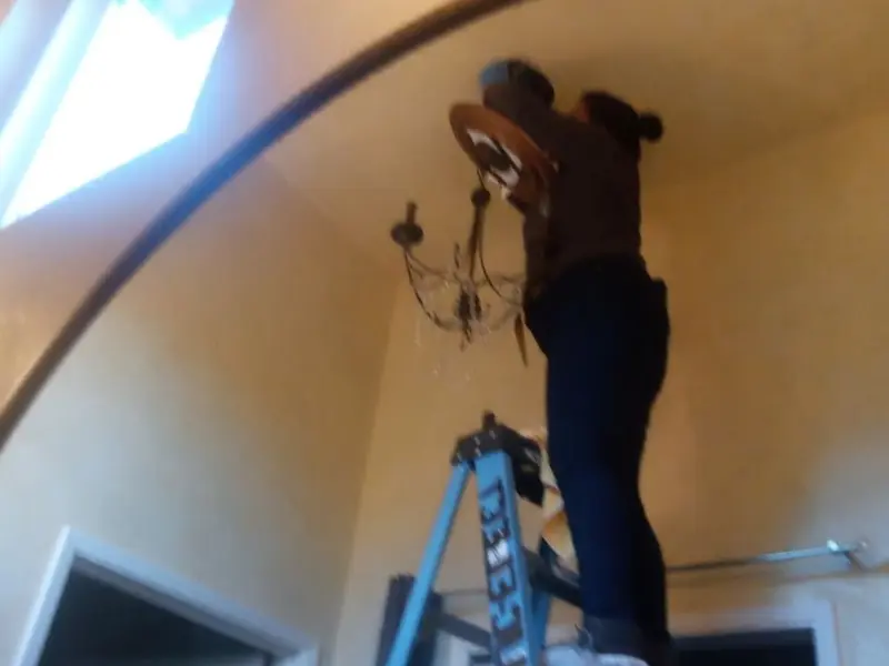 Electrician installing a chandelier in a Santa Fe residence